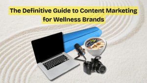 A clean, modern collage featuring a yoga mat, smoothie bowl, laptop, microphone, and camera placed on a textured sand background with concentric patterns. The text “The Definitive Guide to Content Marketing for Wellness Brands” is highlighted in yellow at the top, representing the blend of wellness and digital content creation.